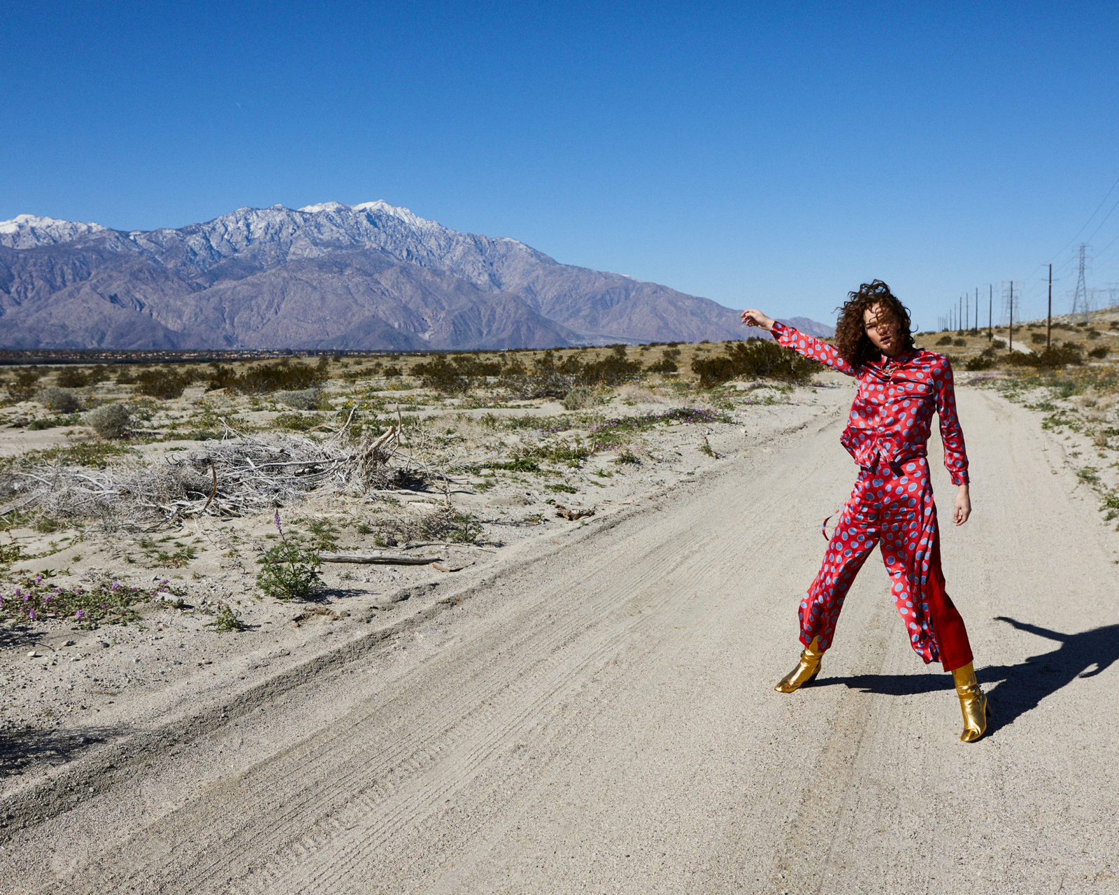 Josh Shinner picture of a woman in pink on an empty road pointing to snowy moutains